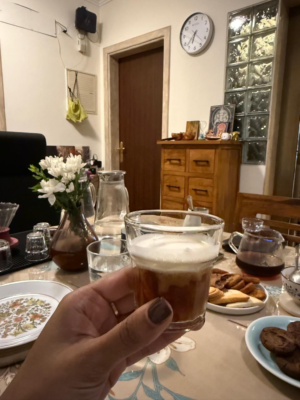 A glass of coffee held over the table at a past Coffee Club